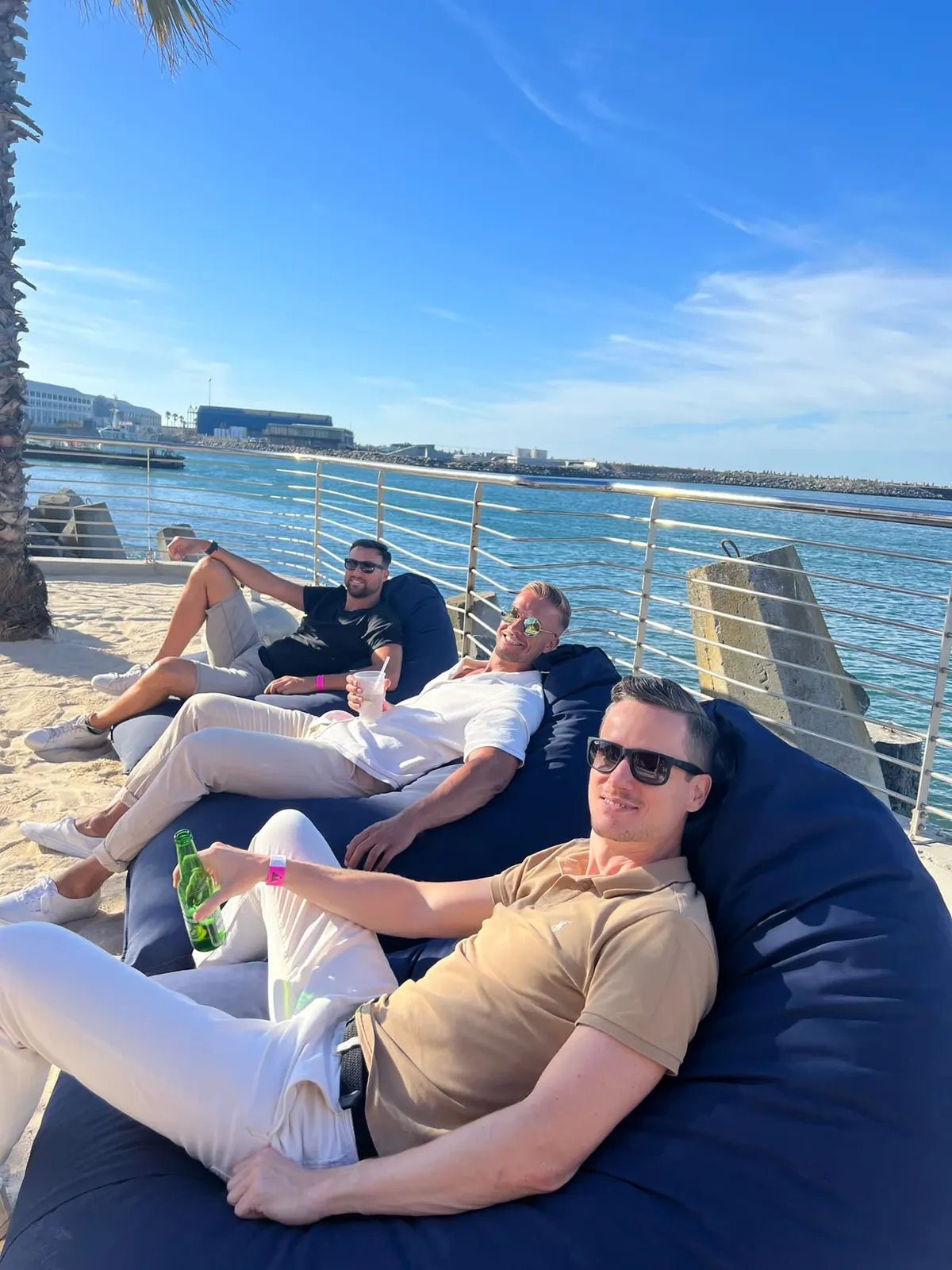 Drei Männer sitzen gemeinsam in Loungesesseln am Hafen