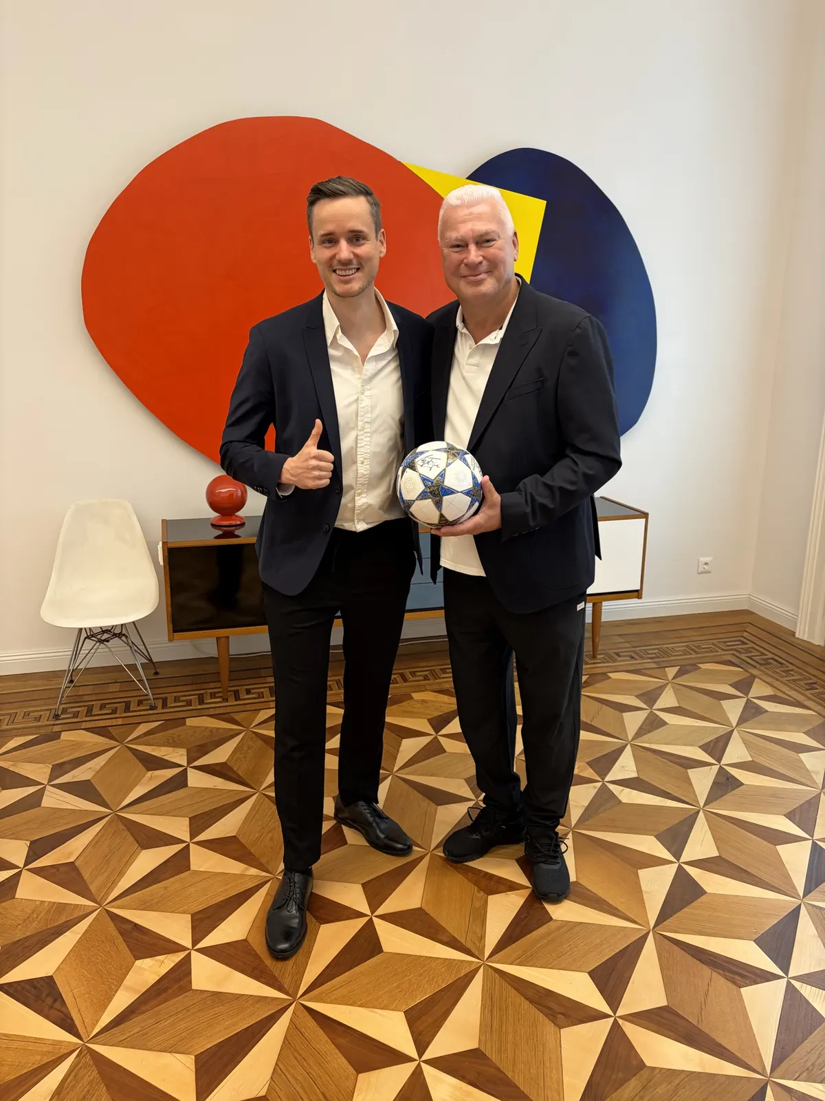 Zwei Männer, einer hält einen Fußball