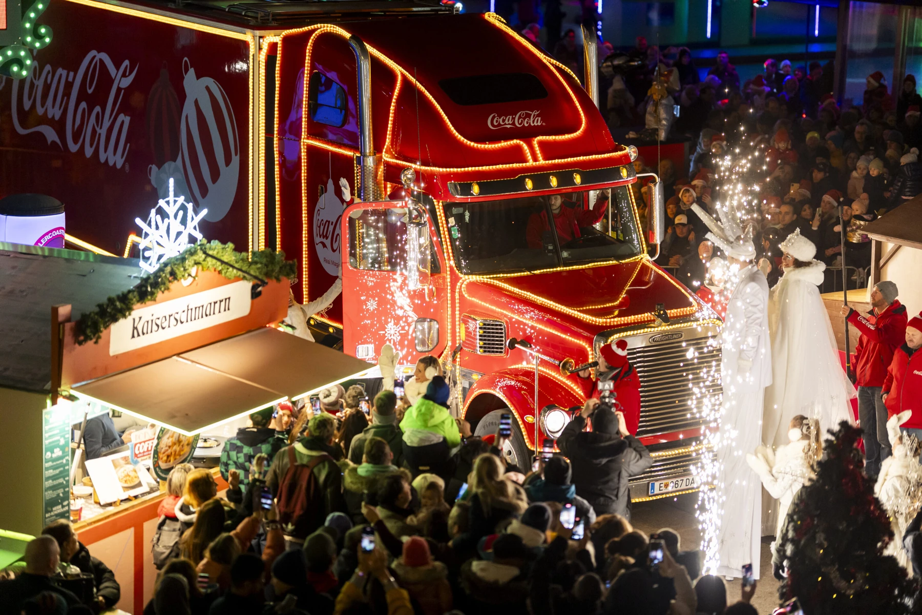 Beleuchteter Coca-Cola-Weihnachtstruck mit Besuchern im Wiener Prater